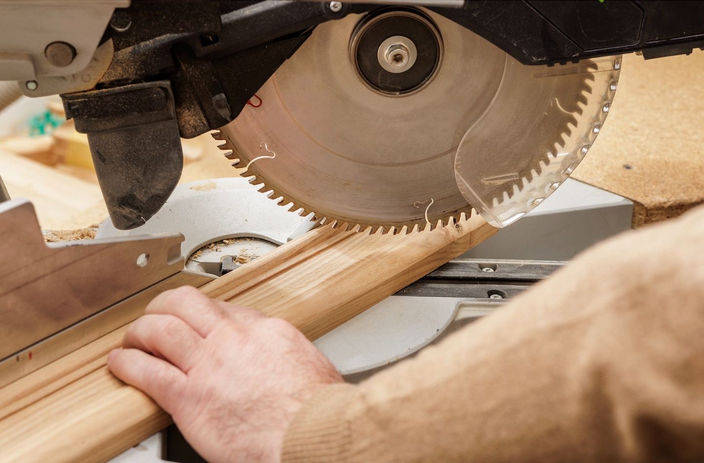 Carpenter cutting trim molding on a miter saw